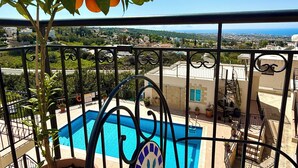 Un balcone con vista su una piscina, una pianta in vaso e un pavimento piastrellato.