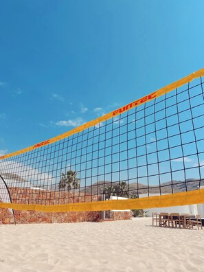 Una red de voleibol de playa con un cielo azul claro al fondo.