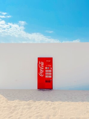 A Coca-Cola vending machine against a plain wall with a clear sky above. - LAS NEGRAS OLIVENCIA NATURAL (Las Negras)