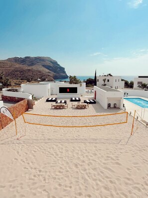 A beachside pool area with a large screen, outdoor seating, and a view of the sea and mountains. - LAS NEGRAS OLIVENCIA NATURAL (Las Negras)