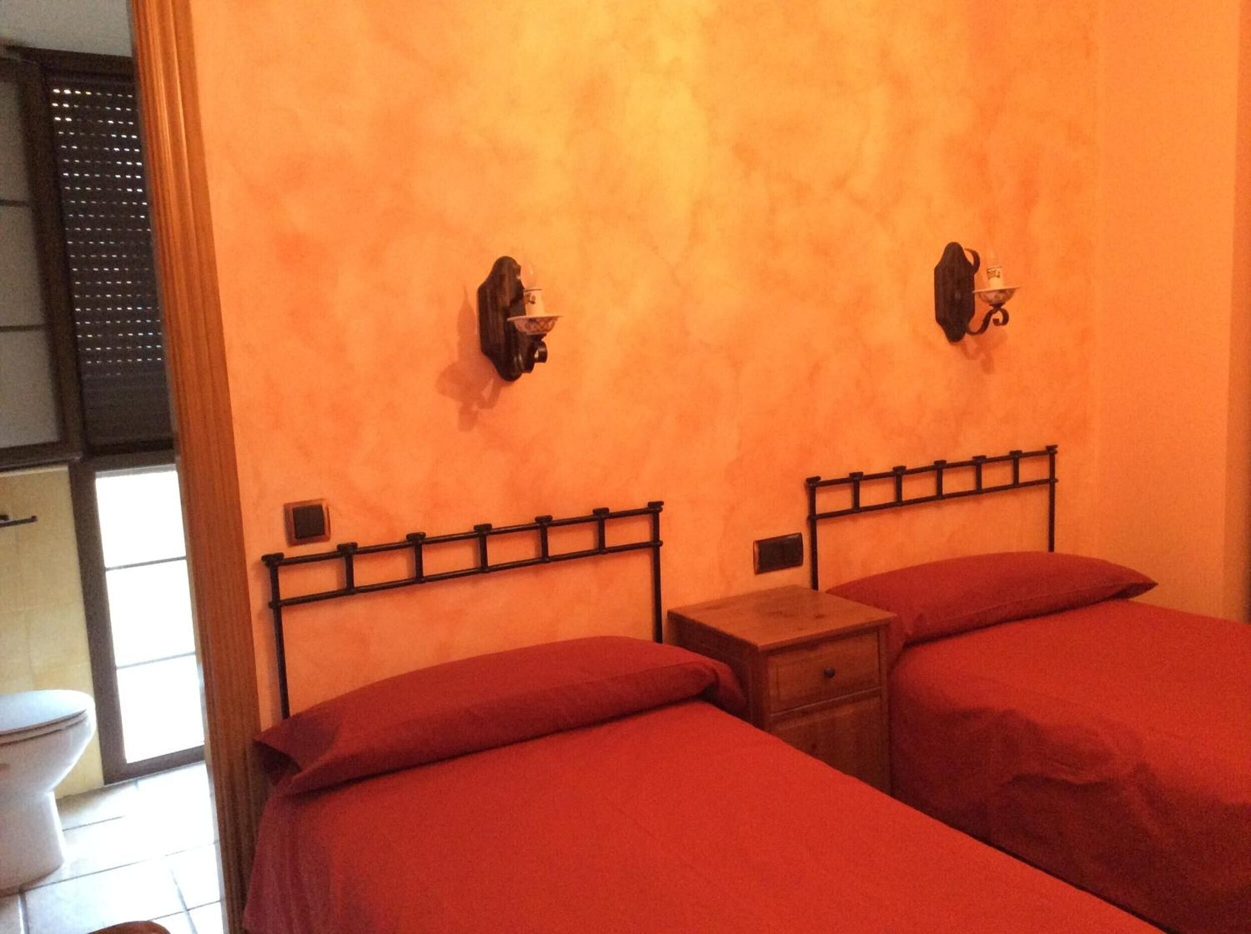 Ein Zimmer mit zwei Betten, einem kleinen Nachttisch und einer Wandleuchte.