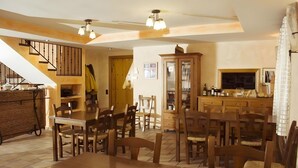 Un espace repas avec des meubles en bois, un escalier et une cuisine équipée d’armoires et d’un téléviseur.