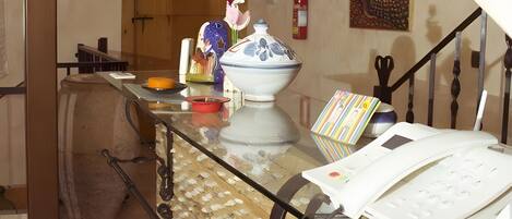 A kitchen with a wooden table, a white telephone, and a vase with flowers.