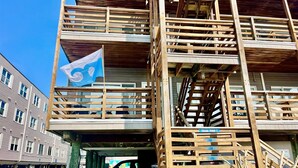 A multi-story building with wooden balconies and a flag. - New for 2026! Ocean Block and Fully Renovated! Comfortably sleeps 6, FREE Linens (Ocean City)