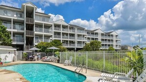 Ein Hotel mit Schwimmbad, Außenbereich zum Sitzen und einem mehrstöckigen Gebäude mit Balkonen.