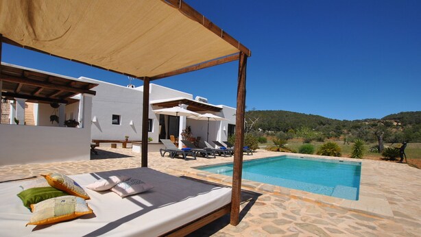 A bed with pillows, a pool, and a view of a hillside. - Charming villa in the middle of nature (Sant Miquel de Balansat)