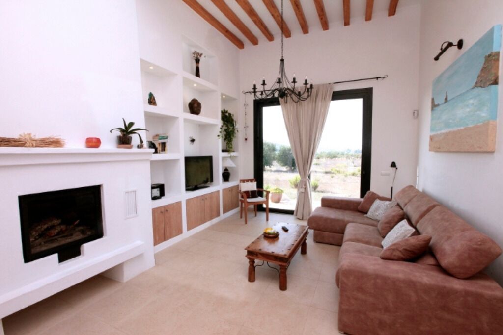 Una sala de estar con chimenea, sofá, televisión y vistas a través de un ventanal.