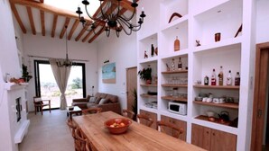 A spacious kitchen with a wooden dining table, white cabinetry, and a variety of kitchenware. - Charming villa in the middle of nature (Sant Miquel de Balansat)