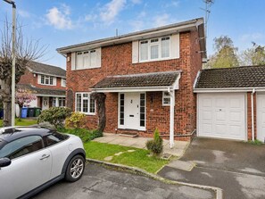 A two-story residential house with a garage, a driveway, and a parked car.