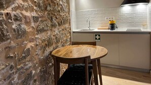 Eine Küche mit einer Steinwand, einem runden Holztisch und einer weißen Fliesenspiegel.