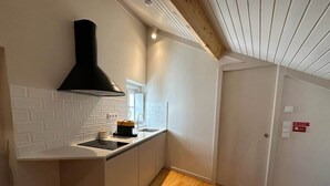 Una cocina con extractor negro, salpicadero de azulejos blancos y suelo de madera.