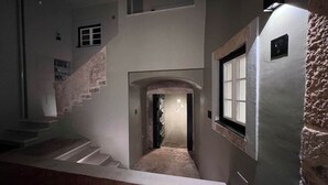 Un pasillo con una escalera, una puerta y una lámpara fijada a la pared.