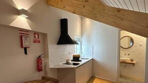 Una cocina compacta con techo de madera, encimera blanca y un lavamanos pequeño.