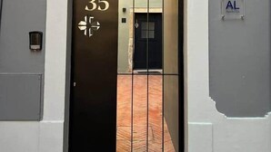 Entrada de un edificio con una puerta negra marcada con el número '35' y un cartel de 'AL' en la pared.