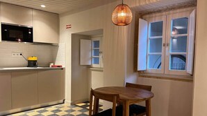 A compact kitchen with a microwave, a coffee machine, and a dining table with chairs. - CorpusChristi 35-12 (Coimbra)