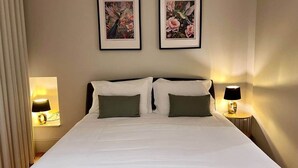 Ein Hotelzimmer mit einem großen Bett, zwei Nachttischlampen und zwei gerahmten Blumenbildern an der Wand.