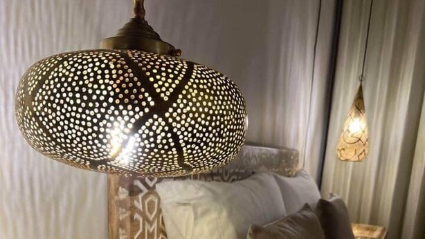 Una cama con almohadas estampadas y una mesita de noche de madera con diseño geométrico.