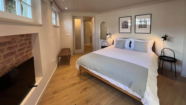 Une chambre avec un grand lit, une cheminée, une télévision et des tableaux encadrés au mur.