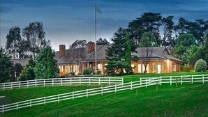 A large house with a white fence in front, surrounded by trees and a flag. - Oak Hill Grand Country Escape with Sunset Views (Chirnside Park)