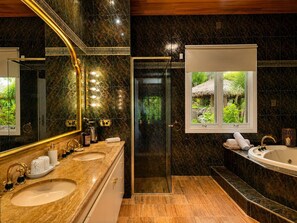 Un baño con dos lavamanos, un espejo grande, una ducha y una ventana con vistas a la vegetación.