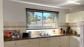 Eine Küche mit weißen Schränken, einem Fenster, einer Spüle und einem Kühlschrank.
