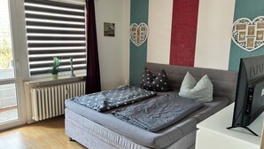 Un dormitorio con cama, un radiador, una ventana con persianas y decoración en la pared.