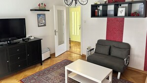 Una sala de estar con televisor, sofá, mesa de centro y candelabro.