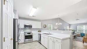 Una cocina moderna con armarios blancos, electrodomésticos de acero inoxidable y una isla central.