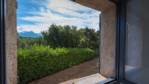 Une vue sur un paysage naturel, avec des arbres et des montagnes, depuis une fenêtre.