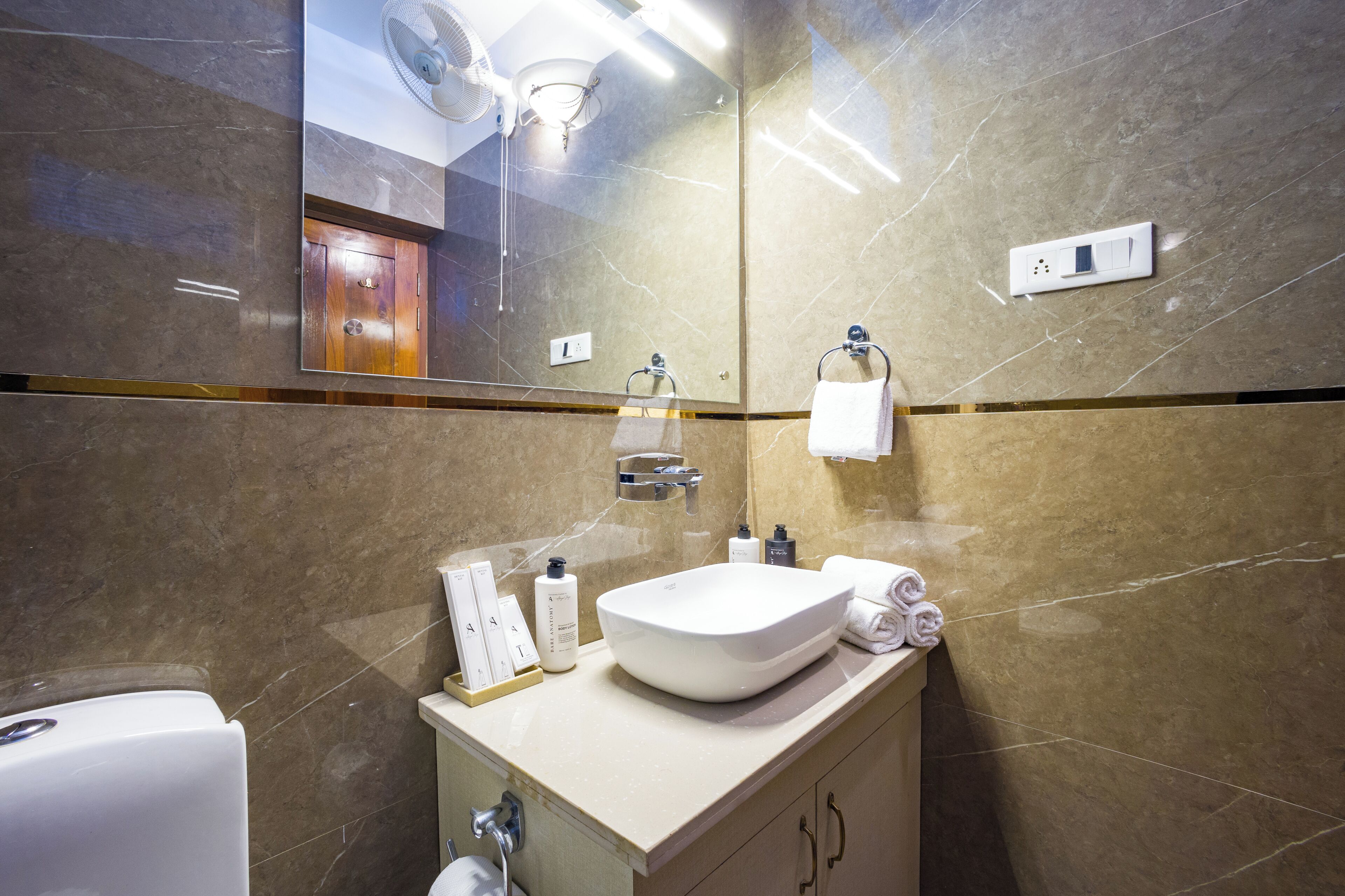 A modern bathroom with a large mirror, a sink, and a toilet.