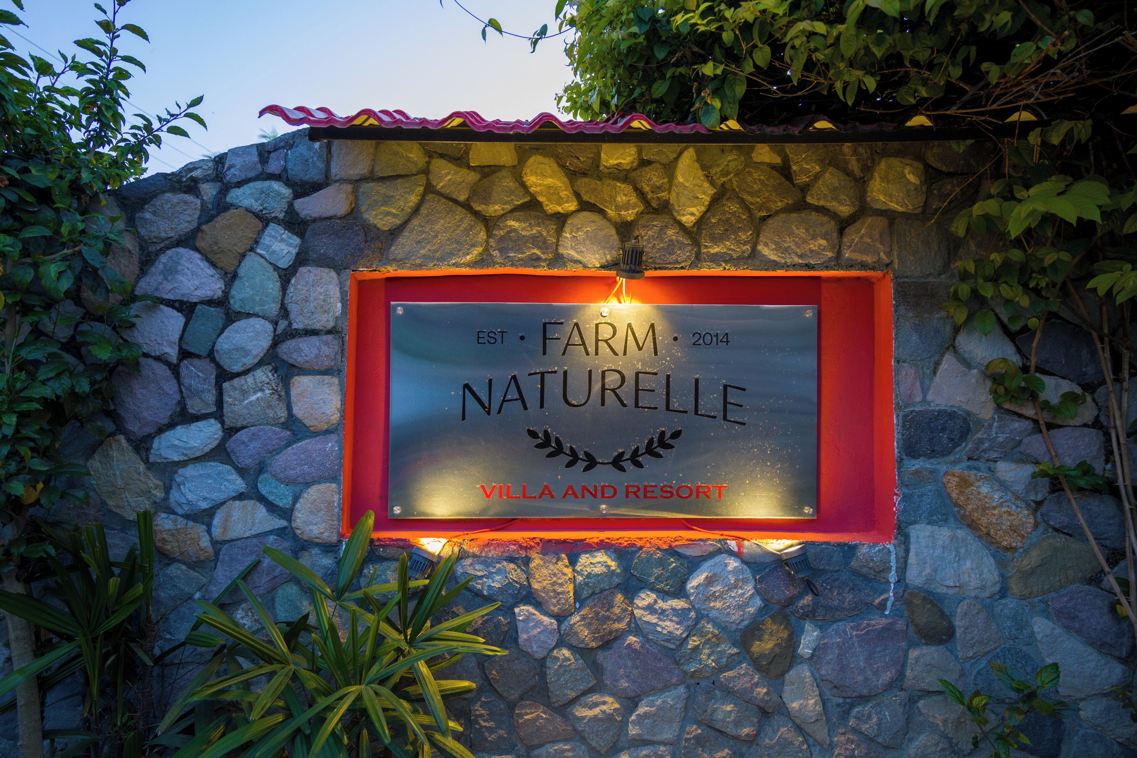 Un muro de piedra con un letrero que dice 'FARM NATURELLE VILLA AND RESORT EST 2014'.
