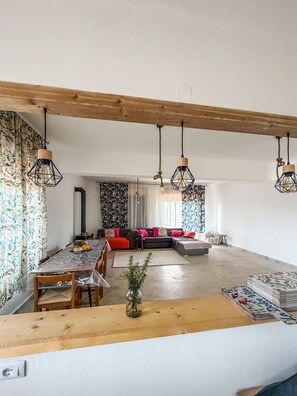 A spacious living area with a dining table, a sofa set, and hanging pendant lights. - Root and Rise - Triple Room with Shared Bathroom (Caltagirone)