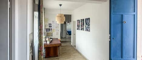 A hallway with a blue door, a wooden table, and a hanging light fixture.