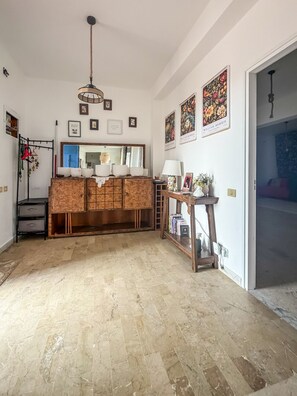 Una habitación amplia con un aparador de madera, una lámpara colgante y cuadros en las paredes.