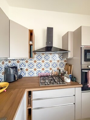 Una cocina equipada con estufa a gas, cafetera y microondas.