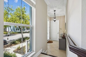 A hallway with a view of a street, a door, a small table with a vase, and a light fixture. - Mangrove Walk-30+ Day Rental in Harbour Isle in Perico (Bradenton)