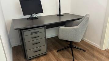 Un bureau moderne, équipé d’un écran, d’un clavier et d’une lampe.