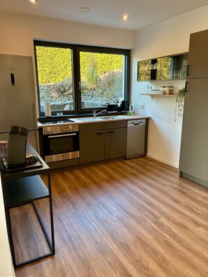 Una cocina moderna con un ventanal grande, electrodomésticos integrados y suelo de madera.