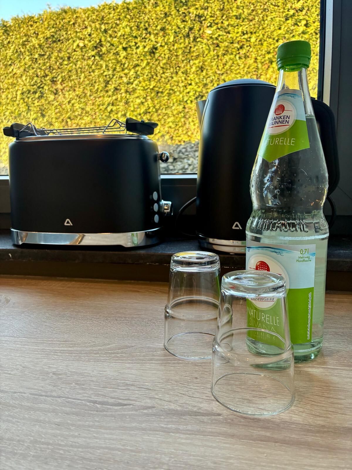 Eine Küche mit Toaster, Wasserkocher und einer Wasserflasche auf einer Holzauskład.