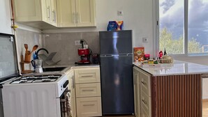 A kitchen with a gas stove, a refrigerator, and wooden cabinets.