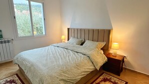 A bedroom with a bed, two bedside lamps, a window, and two rugs.