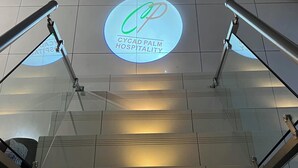Un escalier orné d’un logo circulaire représentant Cycad Palm Hospitality sur le mur.
