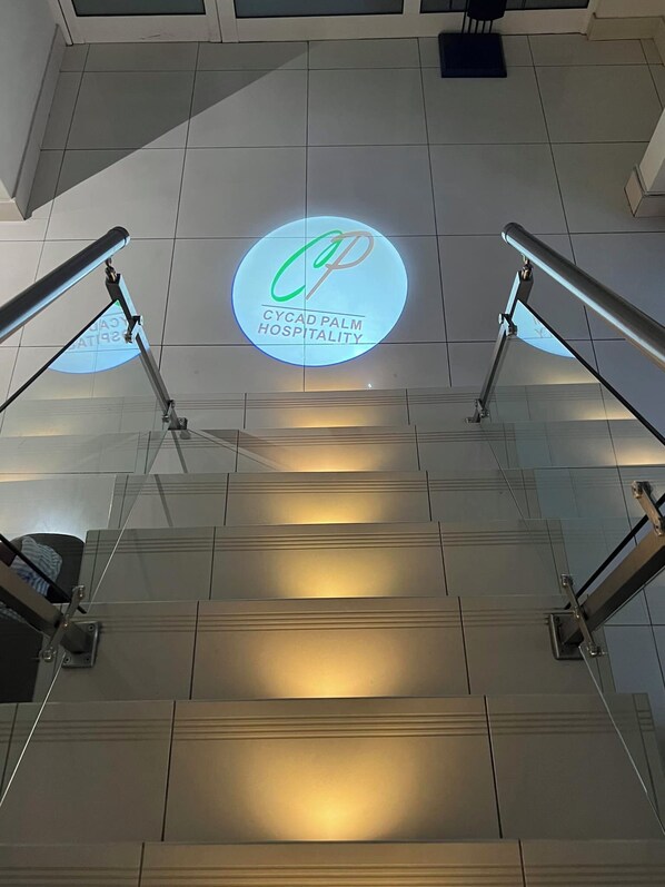 A staircase with a circular logo for Cycad Palm Hospitality on the wall.