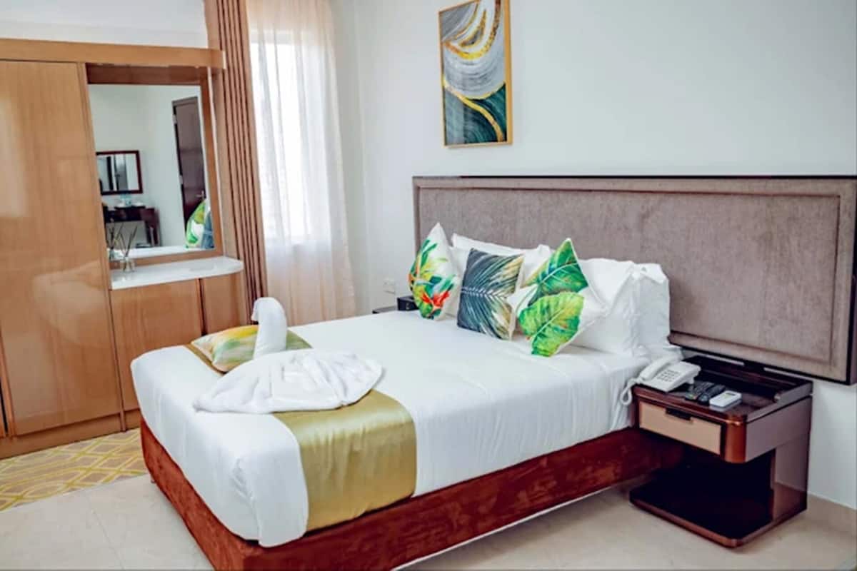 A hotel room with a bed, a nightstand, a telephone, and a mirror.