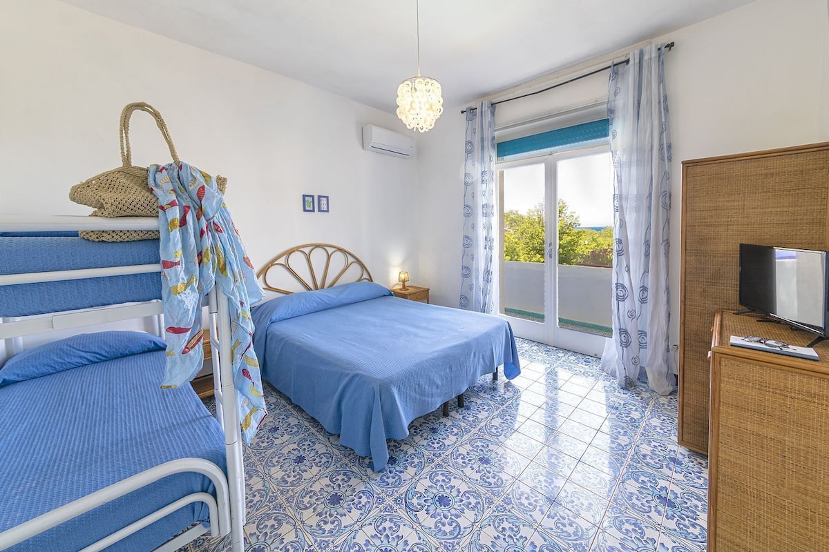 Ein Schlafzimmer mit Etagenbetten, einem Fernseher und einem Balkon mit Vorhängen.