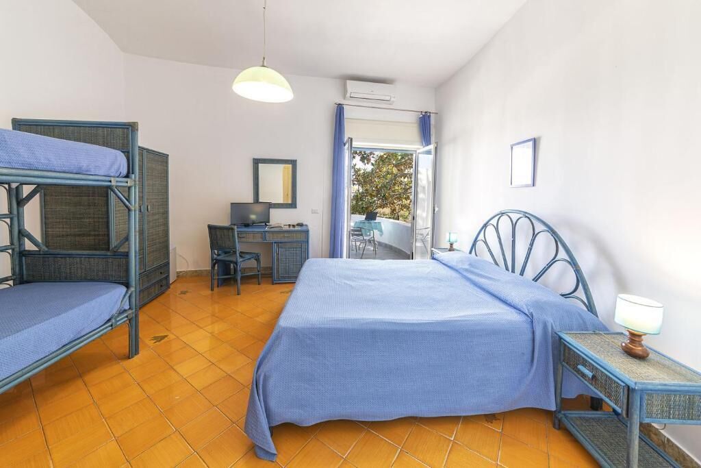 Una habitación con literas, un escritorio, una silla, una lámpara y vistas por la ventana.