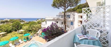 A balcony with a pool, outdoor seating, and a view of the sea.