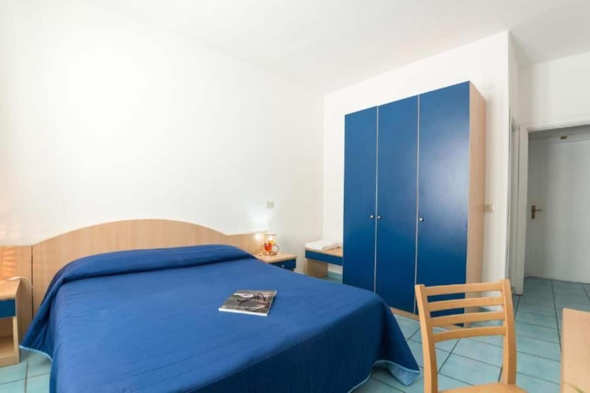 Ein Schlafzimmer mit Bett, Nachttisch, Kleiderschrank und Stuhl.