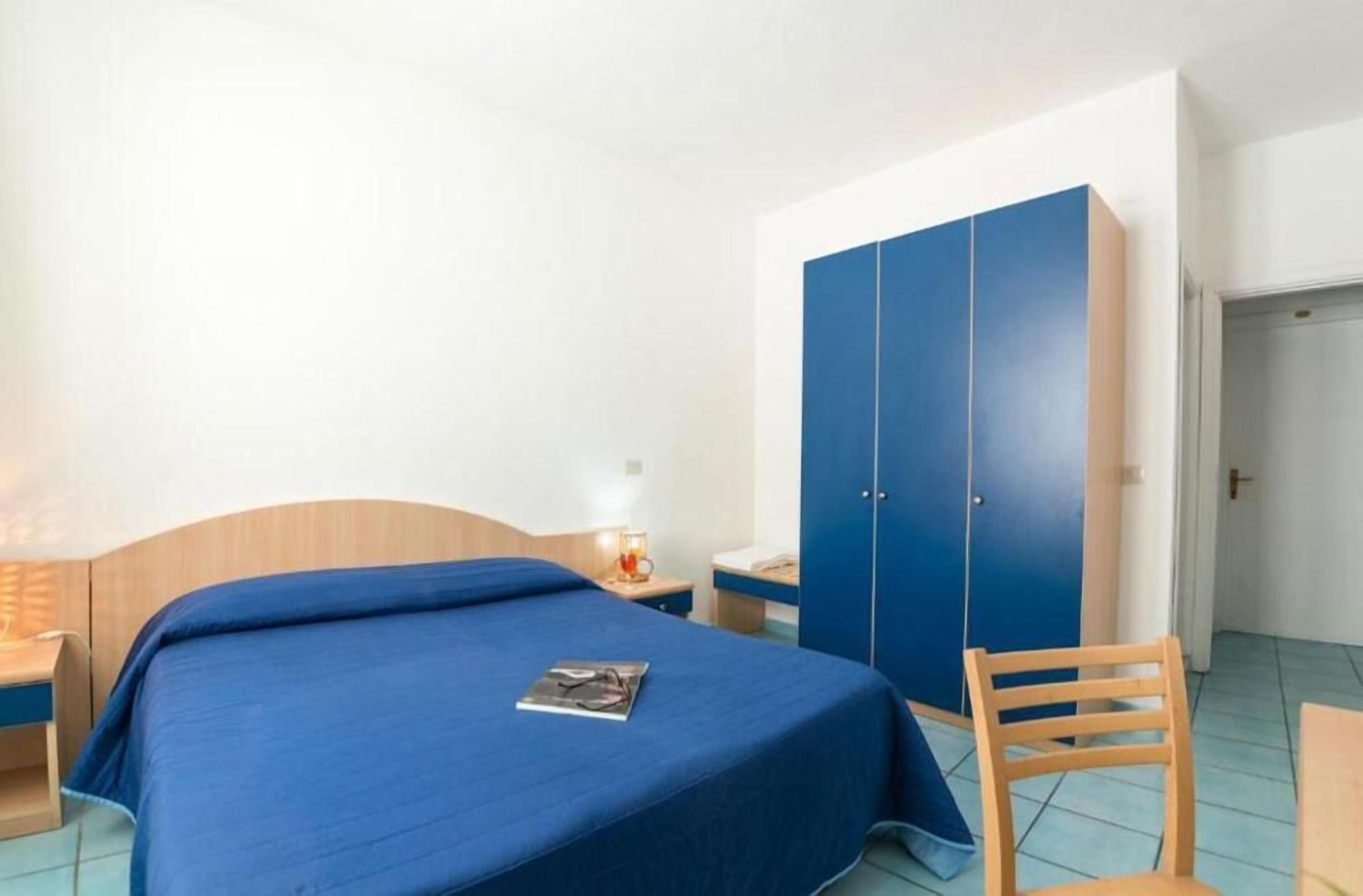 A bedroom with a bed, a nightstand, a wardrobe, and a chair.