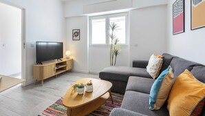 A modern living room with a sofa, TV, wooden side table, and a colorful rug. - Casa Sardinha - in the heart of Portimão (Portimão)